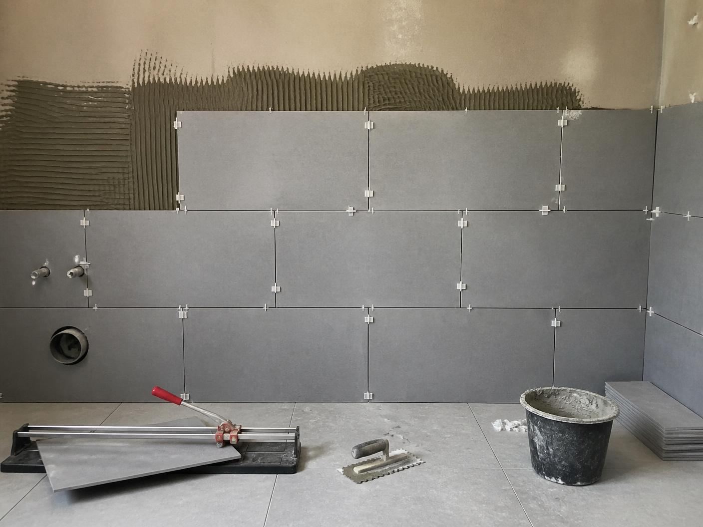 Bathroom wall part tiled with spacers still in place
