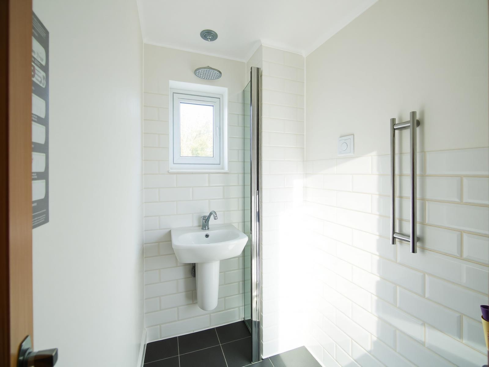 Finished bathroom with white tiled walls, shower screen and wall hung basin